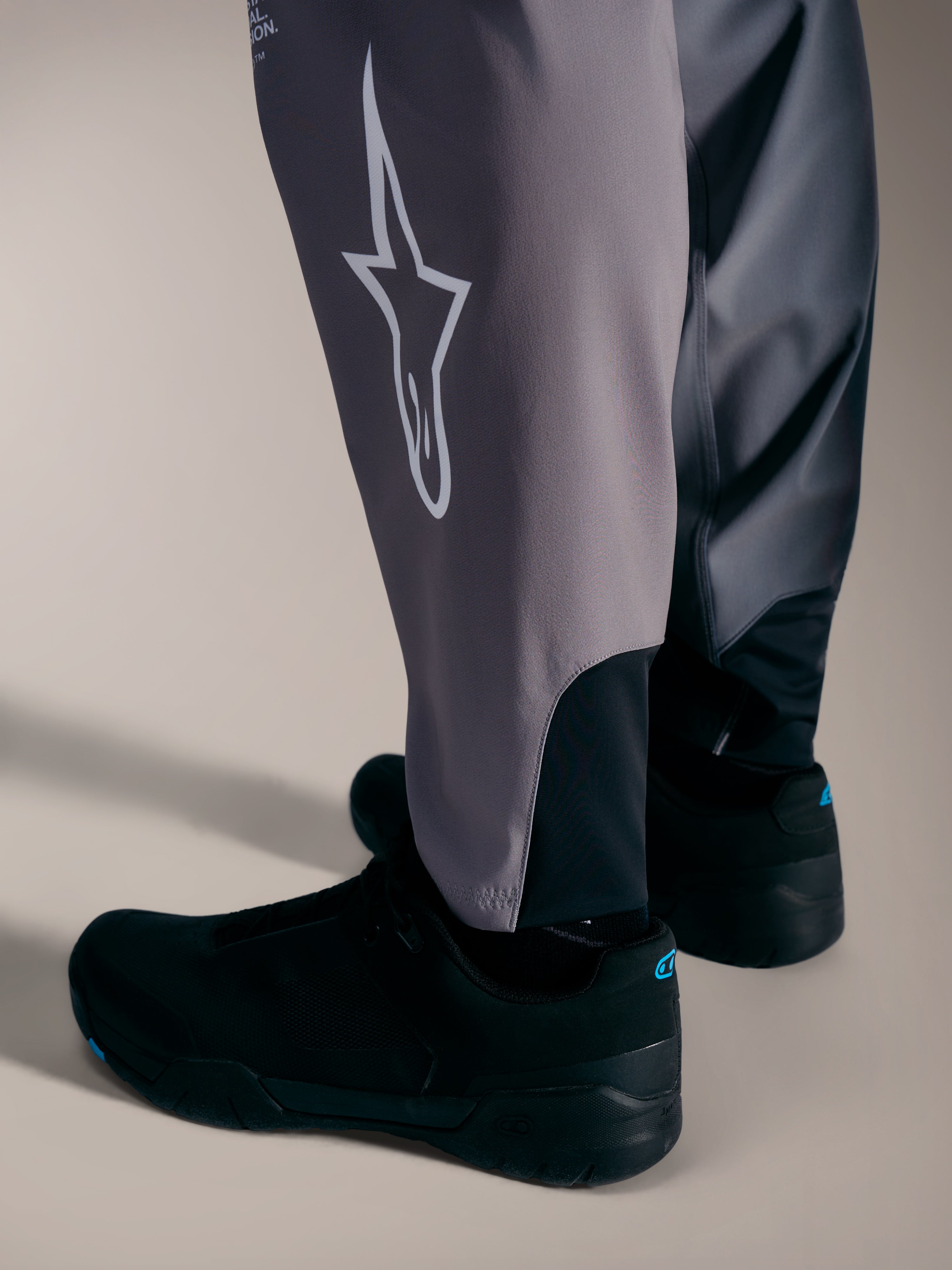 Pantalones A-Supra Elite grises con logotipo Astars blanco y puños elásticos para competición MTB de alto rendimiento.