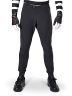 Alpinestars A-Aria Elite Pants, pantalones de MTB en color negro, vista frontal que muestra las perforaciones láser y el cierre de hebilla magnética, usados con jersey de rayas blancas y negras y guantes negros, equipamiento de ciclismo de alto rendimiento para senderos