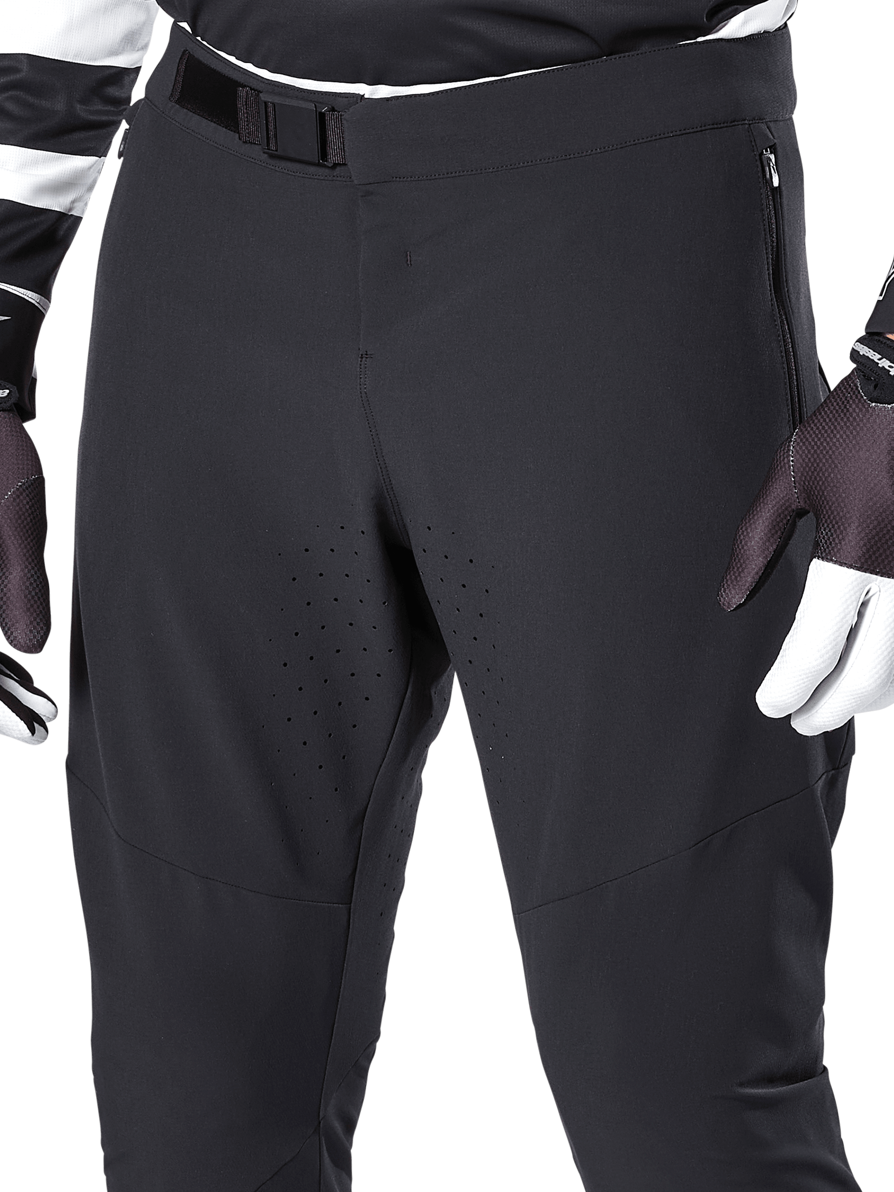 Alpinestars A-Aria Elite Pants, pantalones negros de ciclismo de montaña, primer plano de la cintura frontal y los muslos con cierre de hebilla magnética y orificios de ventilación cortados con láser, combinados con guantes de ciclismo