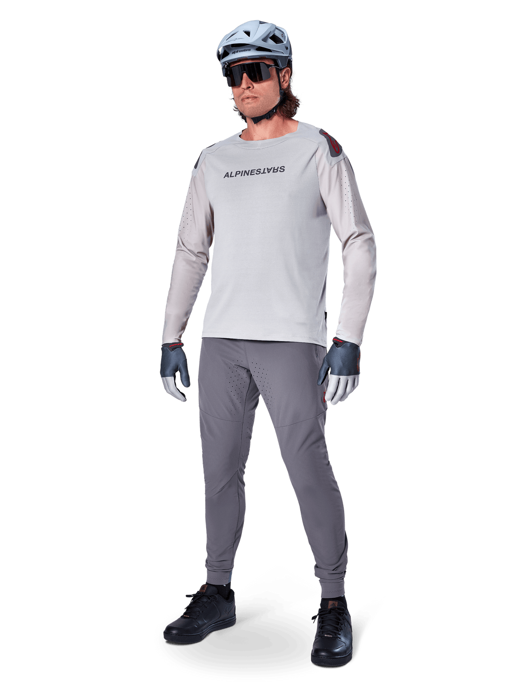 Pantalones Alpinestars A-Aria Elite, pantalones de MTB gris oscuro, usados por un ciclista con jersey de manga larga gris claro y casco gris, con perforaciones láser para ventilación en los muslos y ajuste de rendimiento cónico para ciclismo de montaña