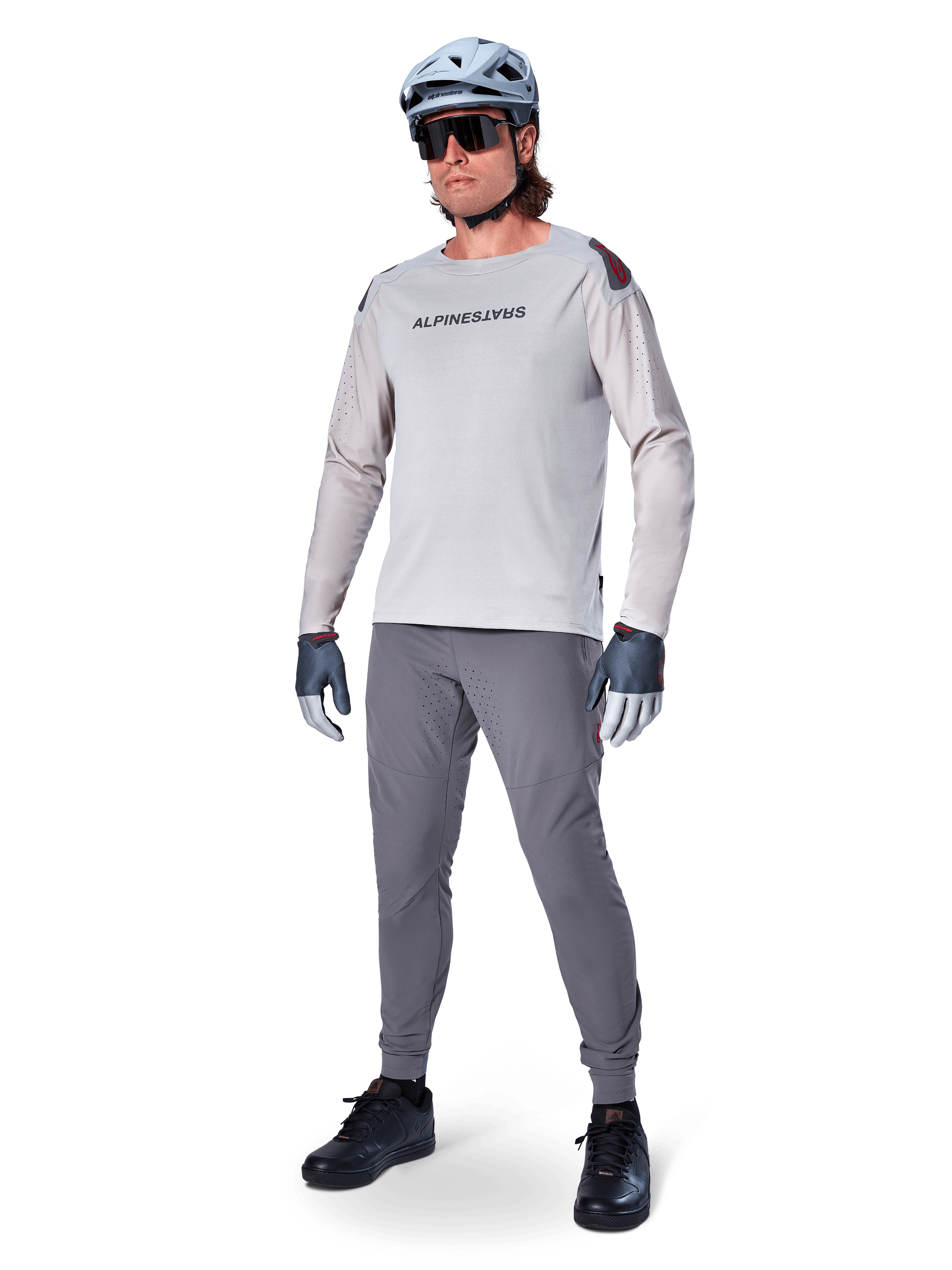 Pantalones Alpinestars A-Aria Elite, pantalones de MTB gris oscuro, usados por un ciclista con jersey de manga larga gris claro y casco gris, con perforaciones láser para ventilación en los muslos y ajuste de rendimiento cónico para ciclismo de montaña