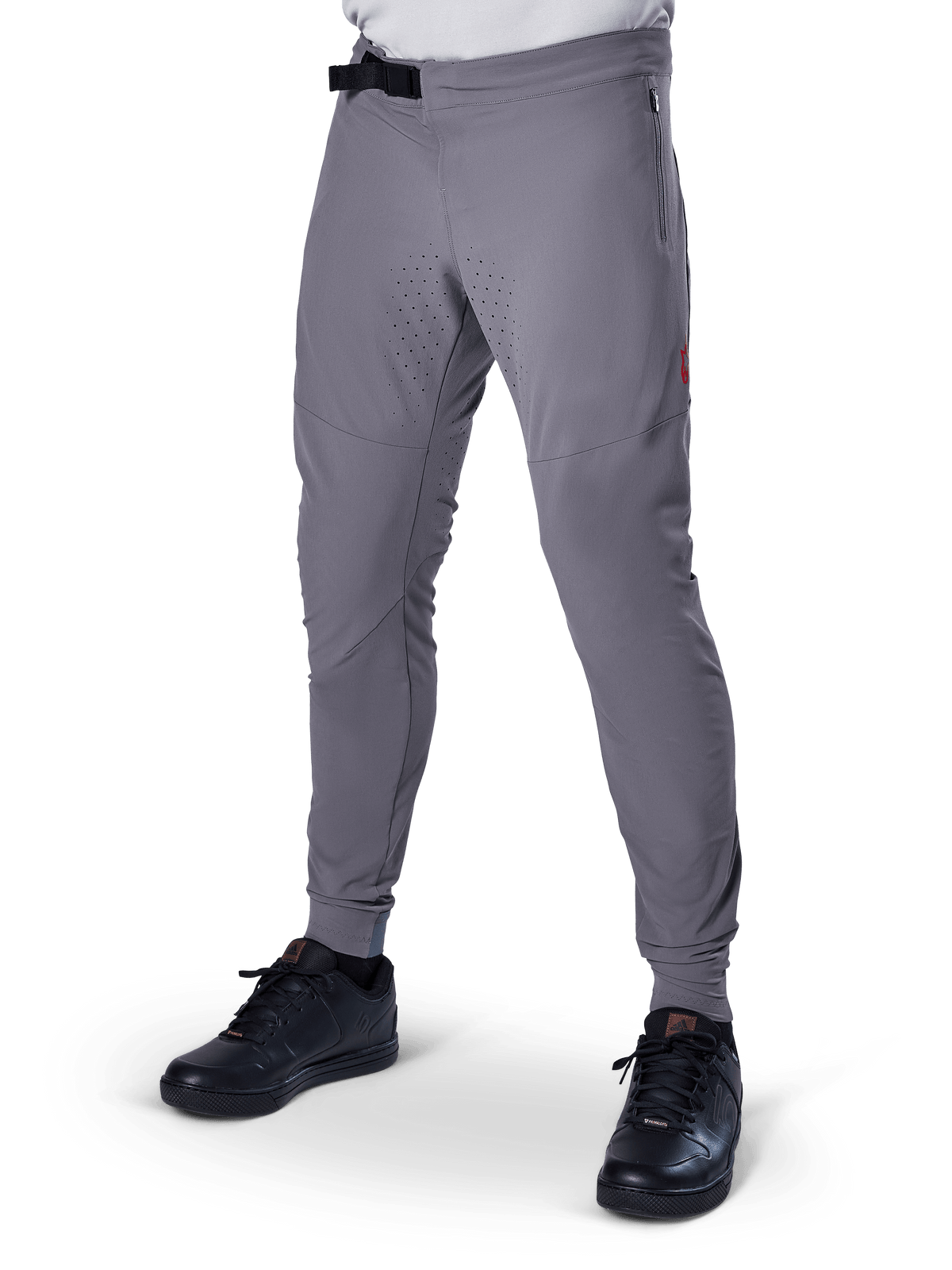 Alpinestars A-Aria Elite Pants, pantalones de MTB gris oscuro, paneles perforados con láser en los muslos, cierre de hebilla magnética negra, bolsillo con cremallera, detalle de logo rojo, ajuste de rendimiento slim, combinados con zapatillas negras