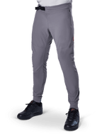 Alpinestars A-Aria Elite Pants, pantalones de MTB gris oscuro, paneles perforados con láser en los muslos, cierre de hebilla magnética negra, bolsillo con cremallera, detalle de logo rojo, ajuste de rendimiento slim, combinados con zapatillas negras