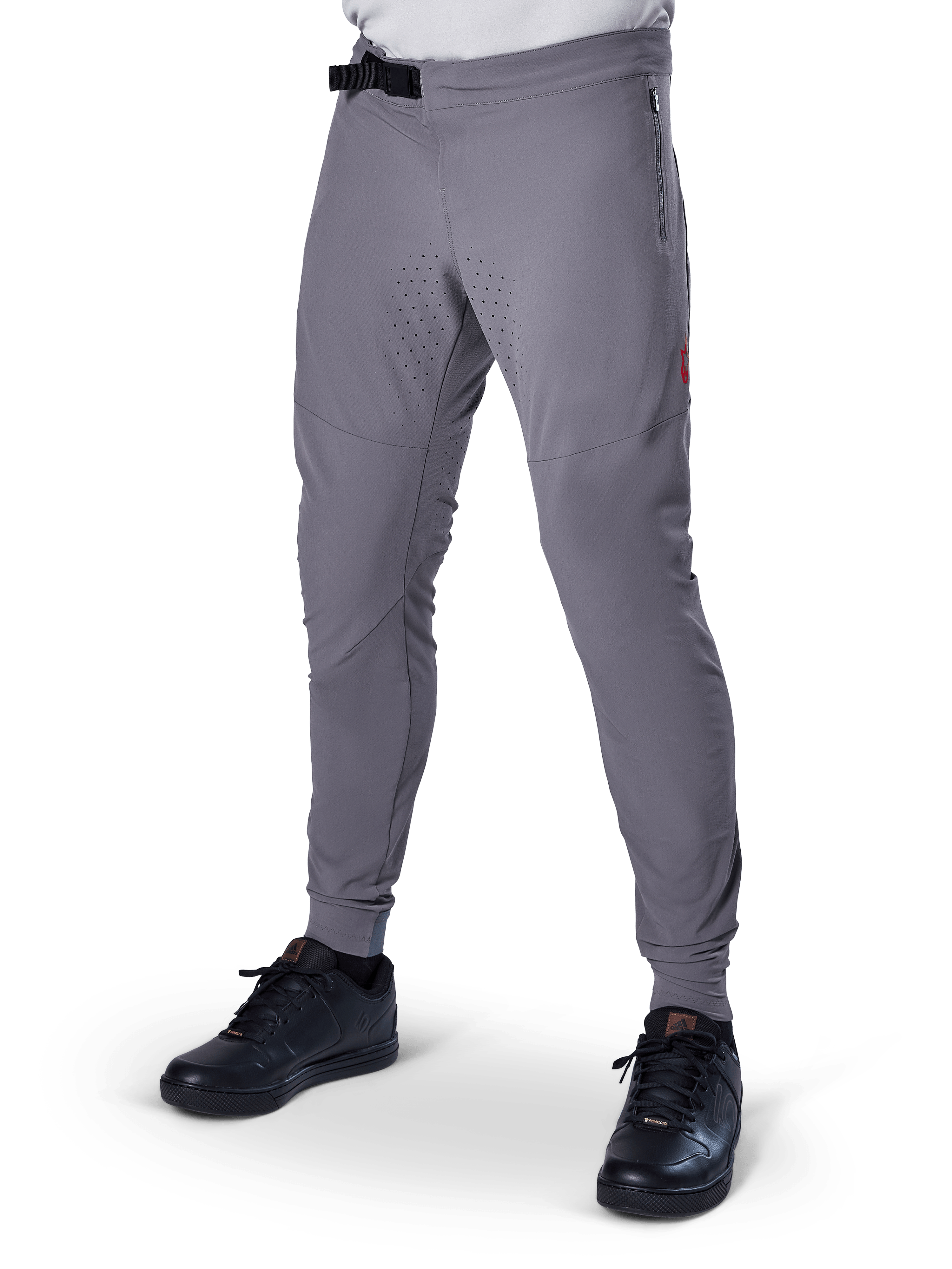 Alpinestars A-Aria Elite Pants, pantalones de MTB gris oscuro, paneles perforados con láser en los muslos, cierre de hebilla magnética negra, bolsillo con cremallera, detalle de logo rojo, ajuste de rendimiento slim, combinados con zapatillas negras