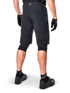 Vista trasera de un ciclista con los shorts Alpinestars A-Aria Elite en color negro, pantalones cortos de alto rendimiento para bicicleta de montaña, combinados con guantes de ciclismo negros y zapatillas negras, diseñados para ofrecer flexibilidad de movimiento en senderos de montaña