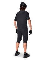 Vista trasera de un ciclista de montaña que viste los shorts Alpinestars A-Aria Elite en negro, combinados con un maillot de manga corta negro a juego, casco negro, guantes y zapatillas de MTB, mostrando un conjunto completo de alto rendimiento para ciclismo de montaña.