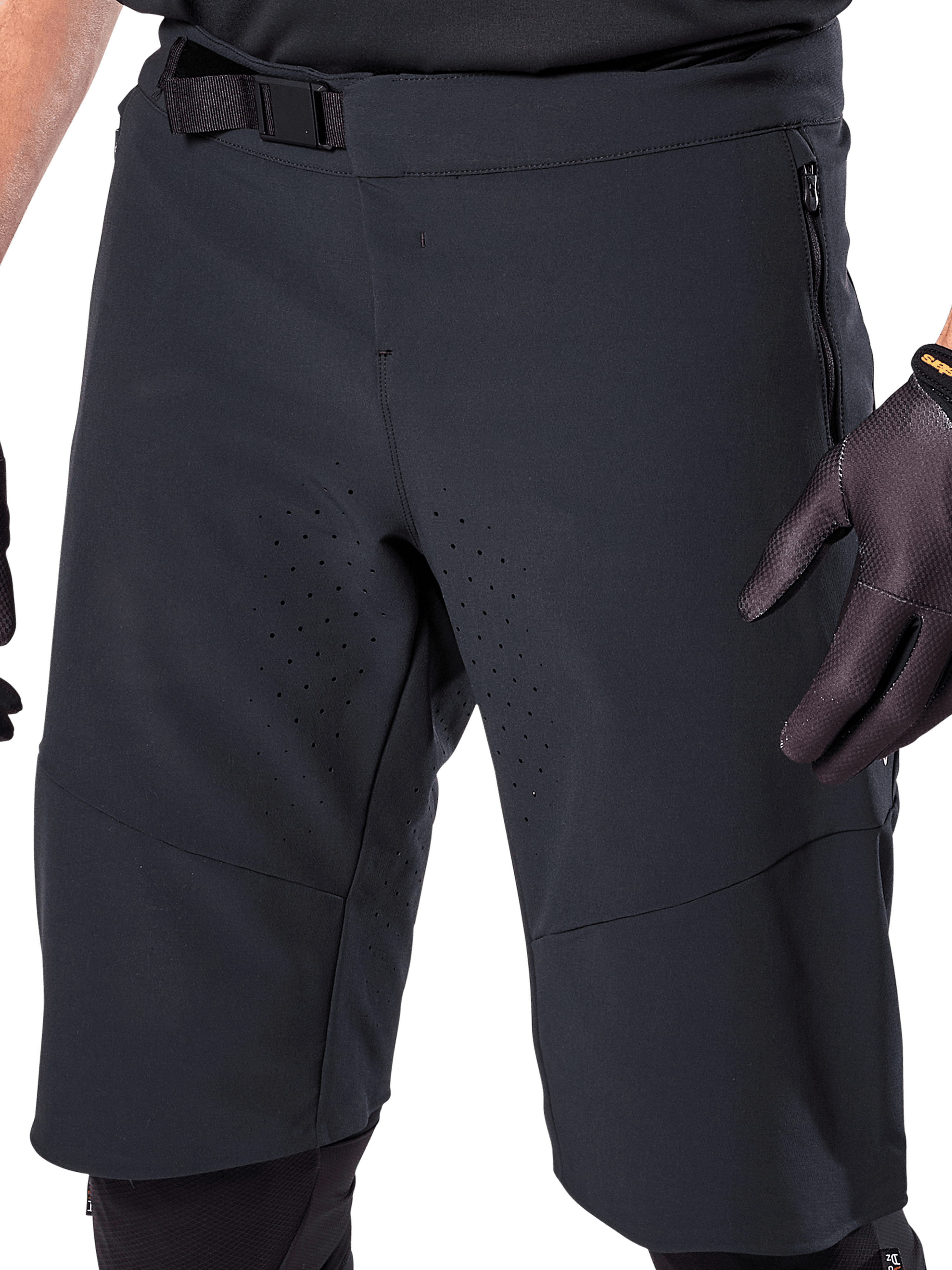 Alpinestars A-Aria Elite Shorts en color negro, vista en primer plano de la zona de la cintura y el muslo, con cierre de hebilla magnética, bolsillos con cremallera y perforaciones de ventilación cortadas con láser, usados con guantes de ciclismo negros para ciclismo de montaña.