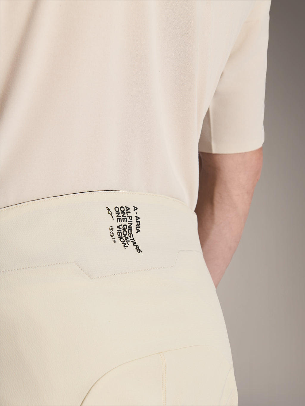 Shorts Alpinestars A-Aria Elite, pantalones cortos de ciclismo de montaña, color crudo, primer plano de la parte posterior de la cintura con el logotipo negro 'A-ARIA ALPINESTARS ONE GOAL. ONE VISION.', ropa de ciclismo de alto rendimiento