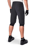 Shorts Alpinestars A-Aria, shorts de ciclismo de montaña, negros, vista trasera que muestra el ajuste de rendimiento y un diseño limpio, usados con guantes negros y calcetines con el logo de Astars en blanco, ropa técnica de ciclismo para conducción off-road