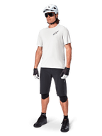 Ciclista de montaña con los shorts Alpinestars A-Aria, shorts de ciclismo negros, combinados con un jersey blanco de manga corta, casco blanco de MTB y equipamiento de rendimiento negro, conjunto completo para trail y senderos