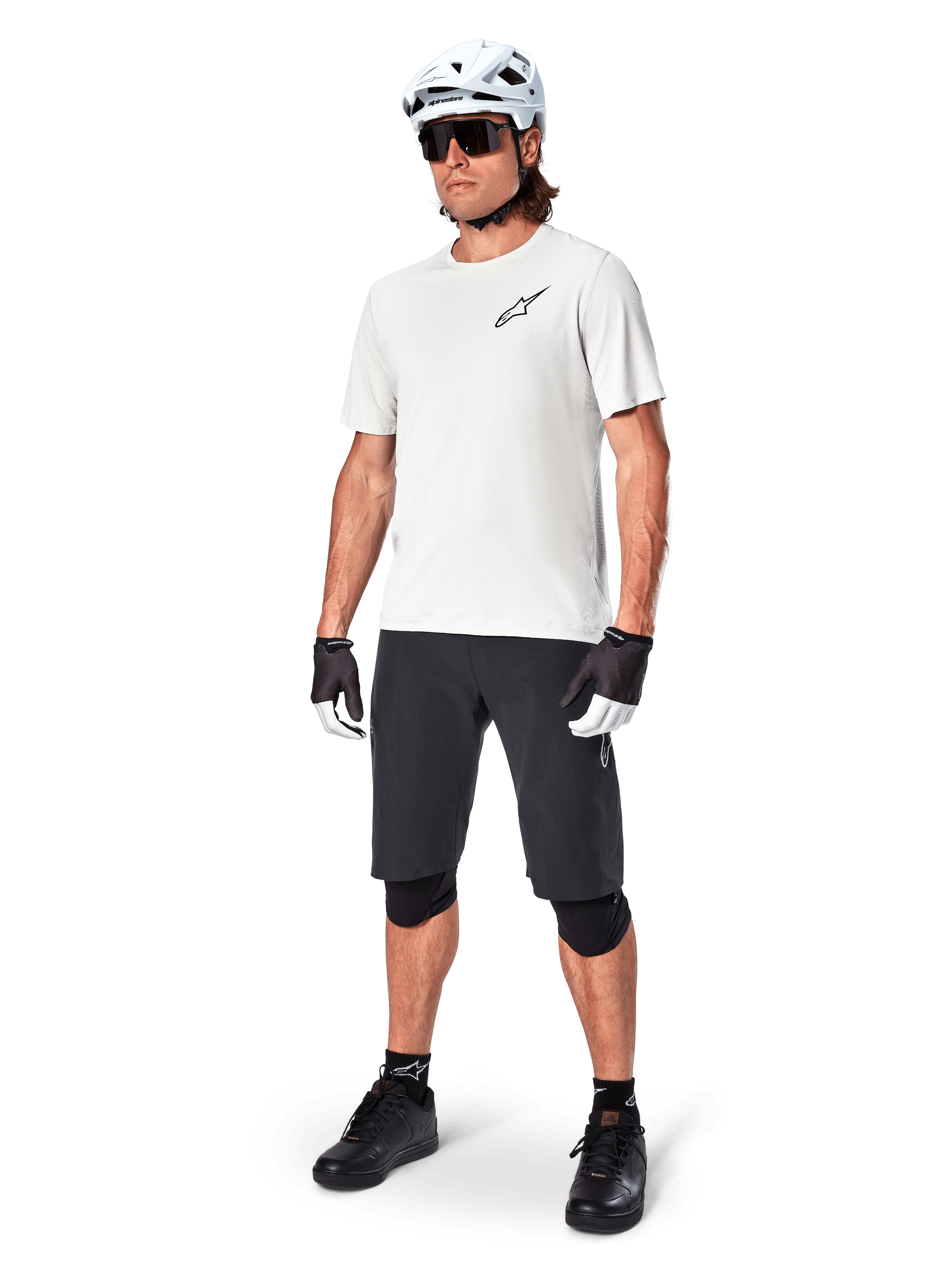 Ciclista de montaña con los shorts Alpinestars A-Aria, shorts de ciclismo negros, combinados con un jersey blanco de manga corta, casco blanco de MTB y equipamiento de rendimiento negro, conjunto completo para trail y senderos