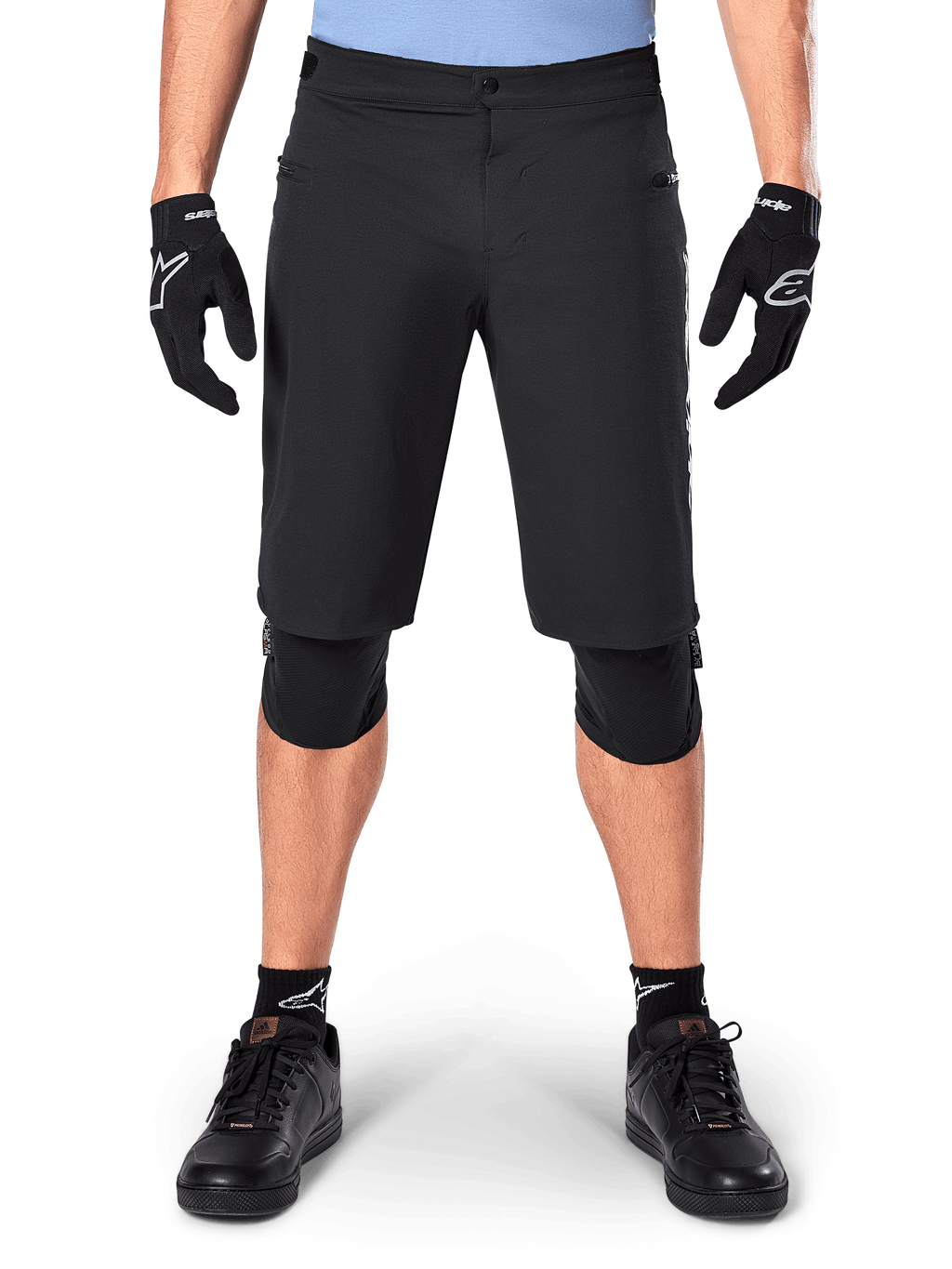 Shorts Alpinestars A-Dura Elite, pantalones cortos negros de mountain bike, usados por un ciclista con guantes negros y rodilleras, con cierre frontal a presión y bolsillos con cremallera, material Cordura duradero para ciclismo de montaña
