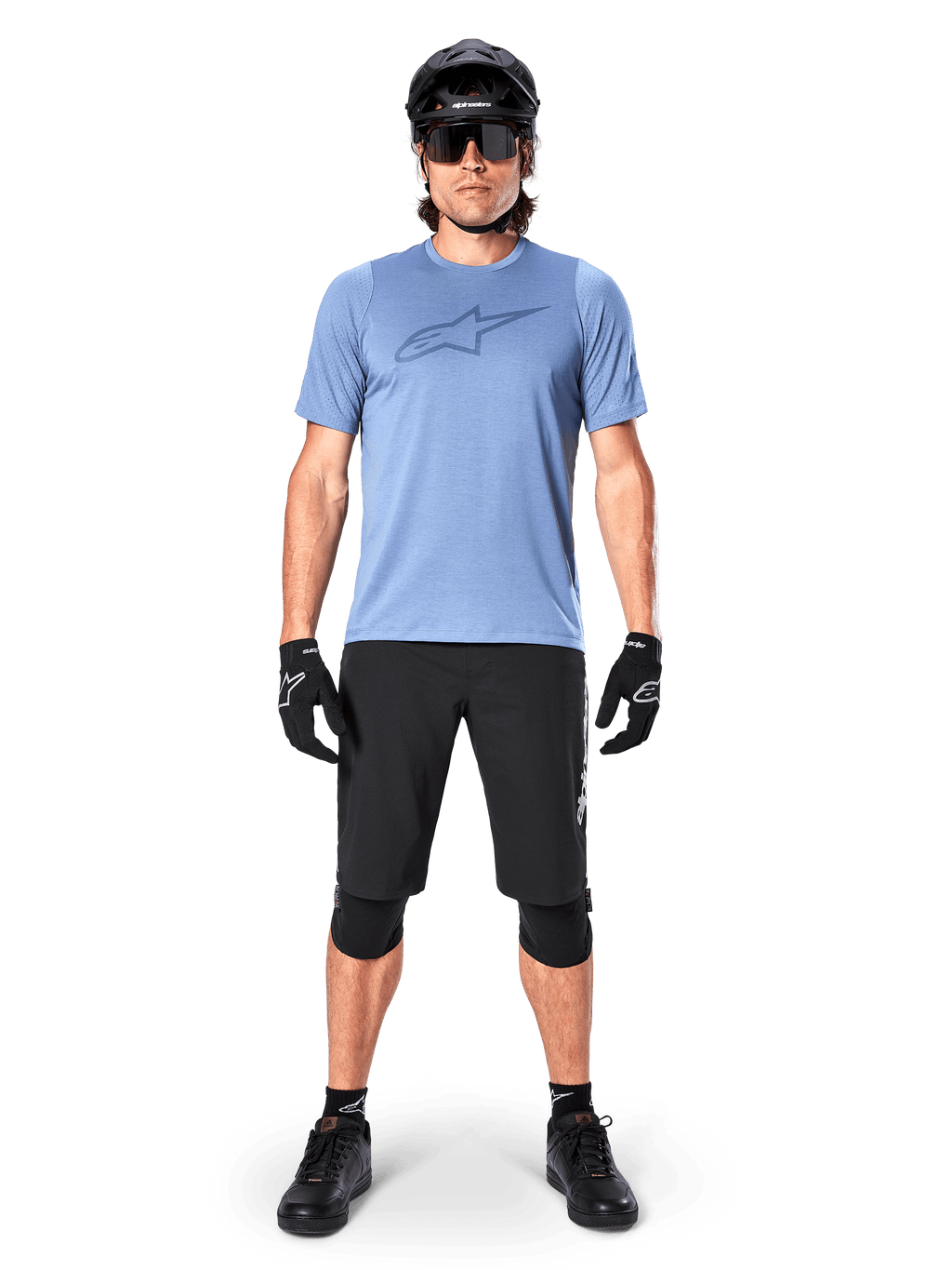 Alpinestars A-Dura Elite Shorts, pantalones cortos de MTB negros, usados con una camiseta azul claro, casco negro, gafas de sol y rodilleras, equipamiento profesional de ciclismo de montaña