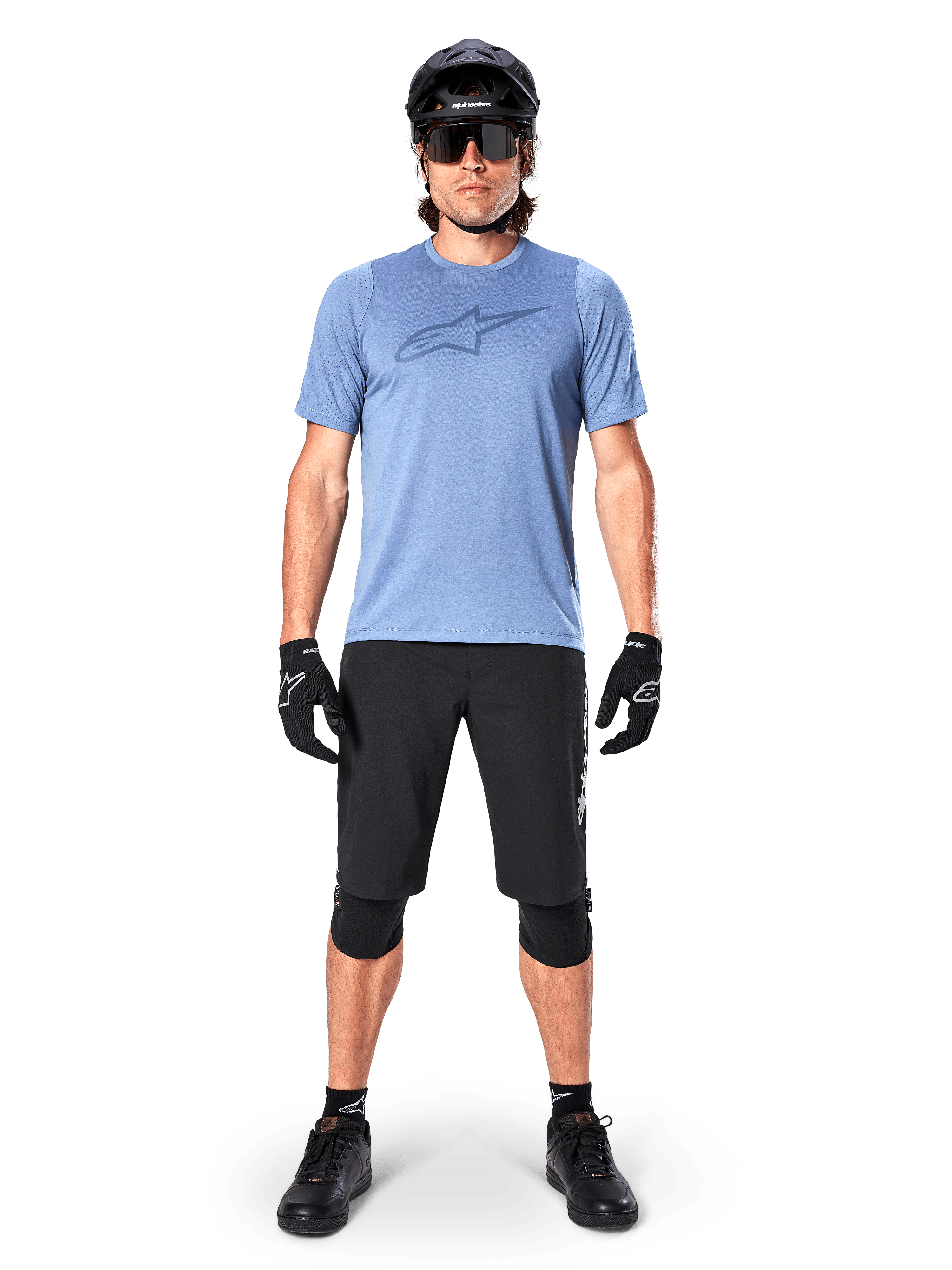Alpinestars A-Dura Elite Shorts, pantalones cortos de MTB negros, usados con una camiseta azul claro, casco negro, gafas de sol y rodilleras, equipamiento profesional de ciclismo de montaña