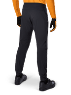Pantalones Alpinestars A-Dura, pantalones de MTB negros, vista trasera, combinados con un jersey de manga larga naranja y guantes negros, con puños elásticos y material textil duradero para ciclismo de montaña.