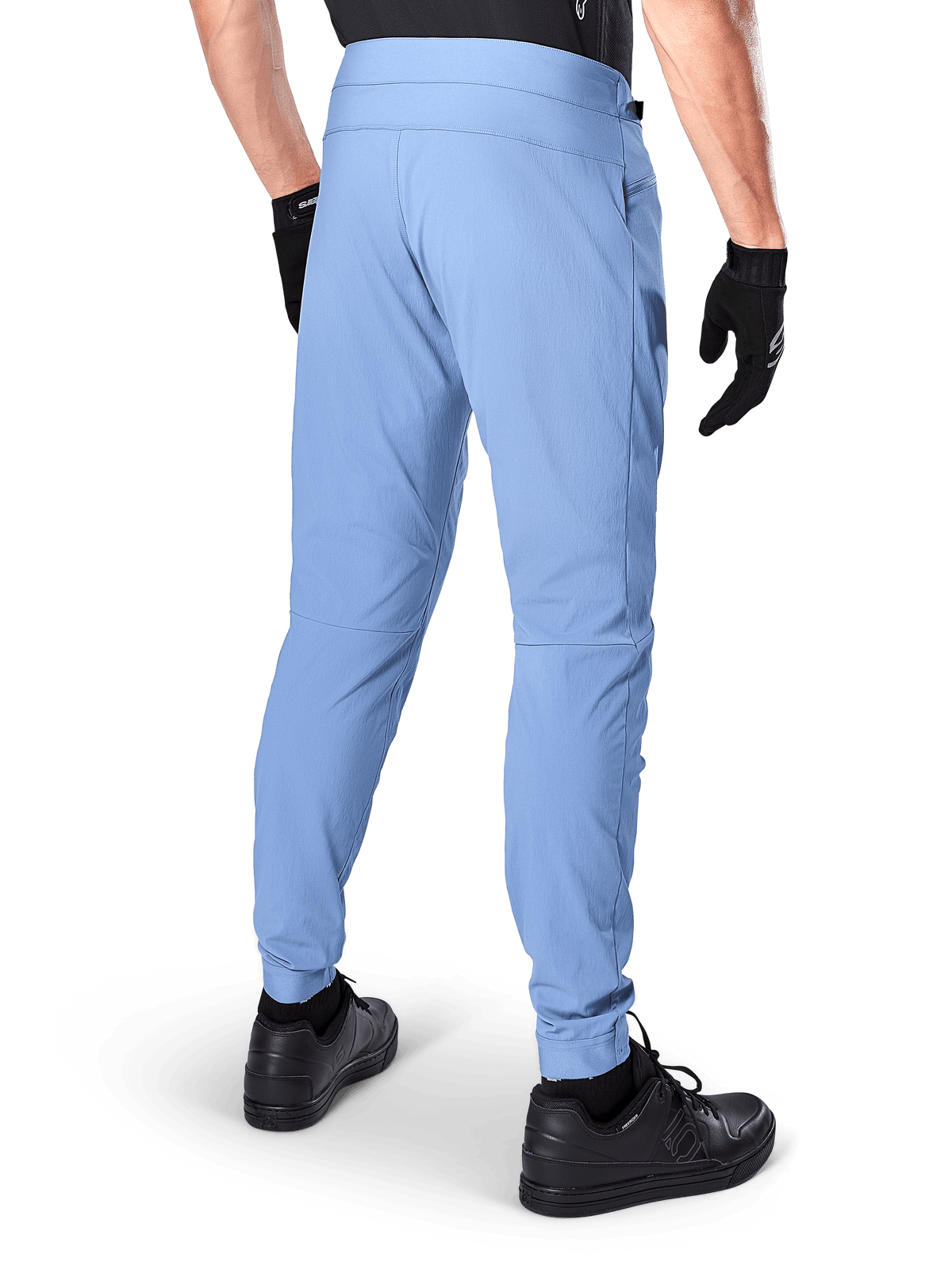 Pantalones Alpinestars A-Dura, pantalones de ciclismo de montaña, color Azul Infinity, vista trasera que muestra el ajuste regular y los puños elásticos, usados con guantes y calzado negros, ropa de ciclismo duradera con tejido elástico en 2 direcciones.