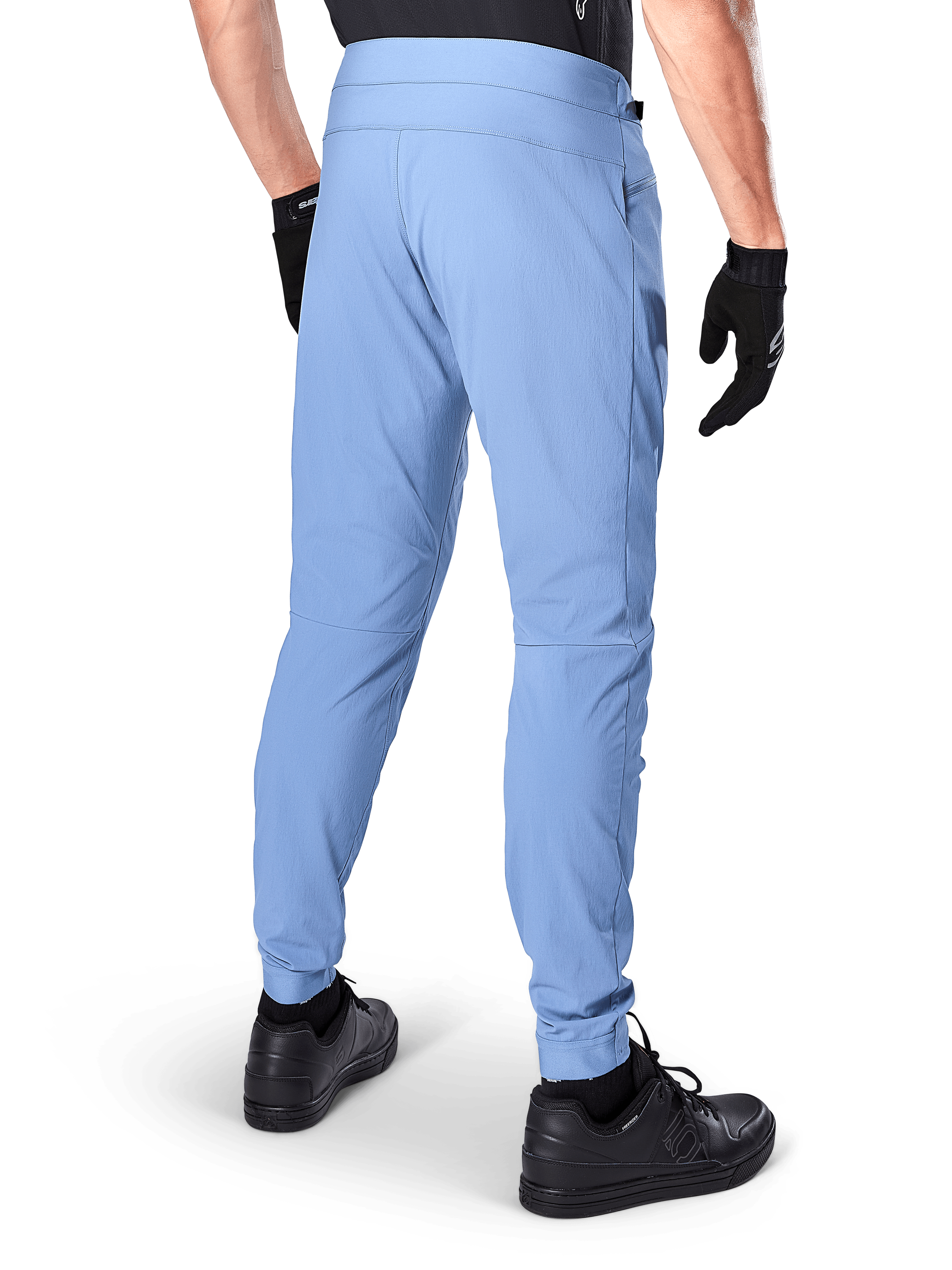 Pantalones Alpinestars A-Dura, pantalones de ciclismo de montaña, color Azul Infinity, vista trasera que muestra el ajuste regular y los puños elásticos, usados con guantes y calzado negros, ropa de ciclismo duradera con tejido elástico en 2 direcciones.