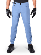 Pantalones Alpinestars A-Dura, pantalones de MTB, Infinity Blue, pantalones de ciclismo de montaña azul claro con cierre de doble broche y bolsillos con cremallera, usados con guantes negros y zapatillas negras, ajuste regular con puños elásticos