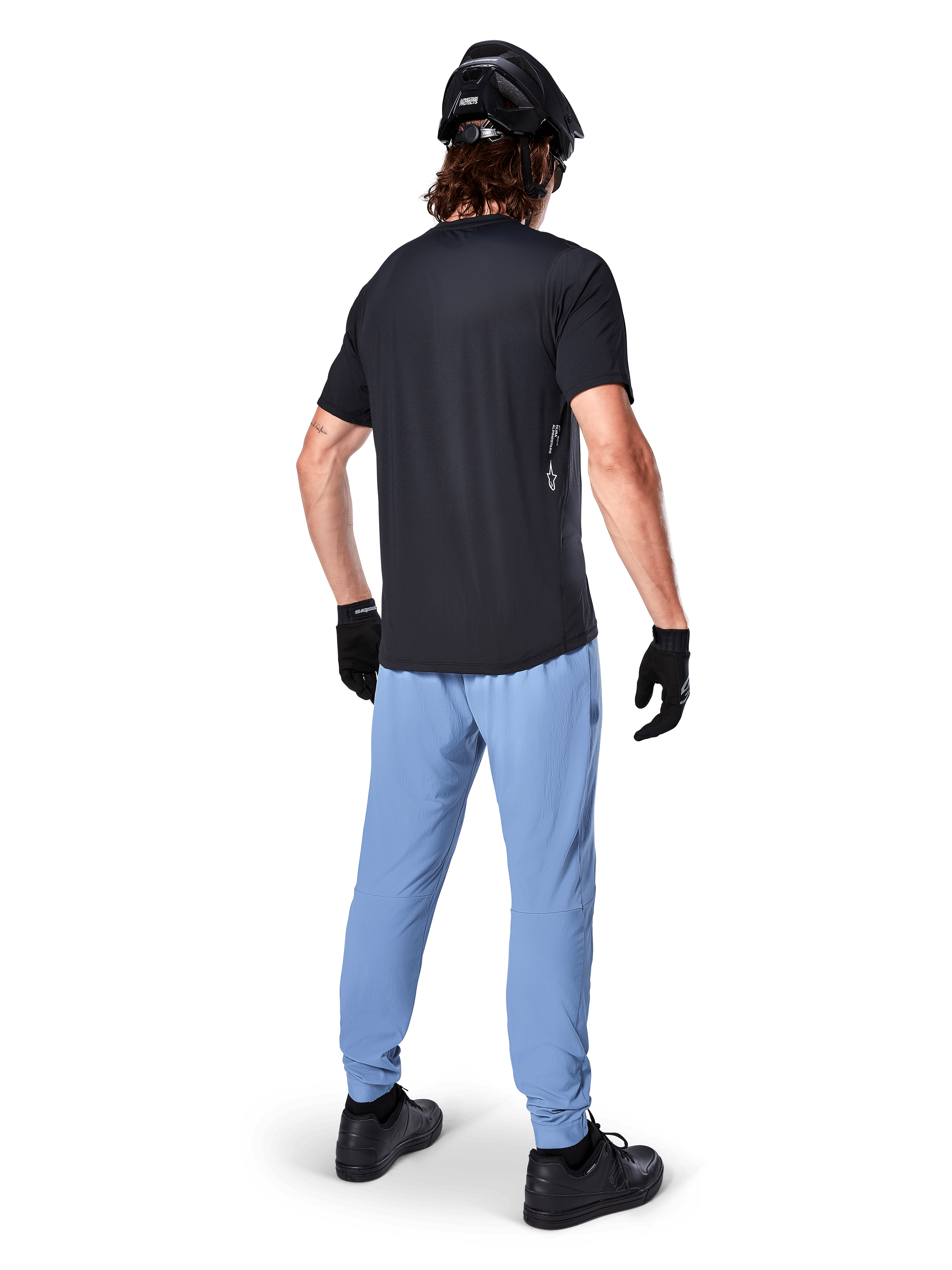 Pantalones Alpinestars A-Dura, pantalones de MTB, Azul Infinity, vista trasera en modelo con camiseta negra y casco de ciclismo negro, con tejido elástico duradero en 2 direcciones y puños elásticos, equipamiento de alto rendimiento para ciclismo de montaña