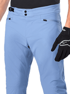 Pantalones Alpinestars A-Dura, pantalones de ciclismo MTB, Azul Infinity, primer plano de la cintura con cierre de doble broche y ajustador lateral, bolsillos con cremallera, usados con guantes Alpinestars negros