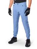 Alpinestars A-Dura Pants, pantalones de ciclismo MTB en color Infinity Blue, con cierre frontal de doble botón a presión y bolsillos con cremallera, combinados con guantes negros y calzado negro, tejido elástico en 2 direcciones duradero para ciclismo de montaña