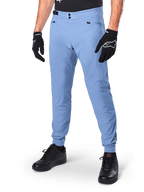Alpinestars A-Dura Pants, pantalones de ciclismo MTB en color Infinity Blue, con cierre frontal de doble botón a presión y bolsillos con cremallera, combinados con guantes negros y calzado negro, tejido elástico en 2 direcciones duradero para ciclismo de montaña
