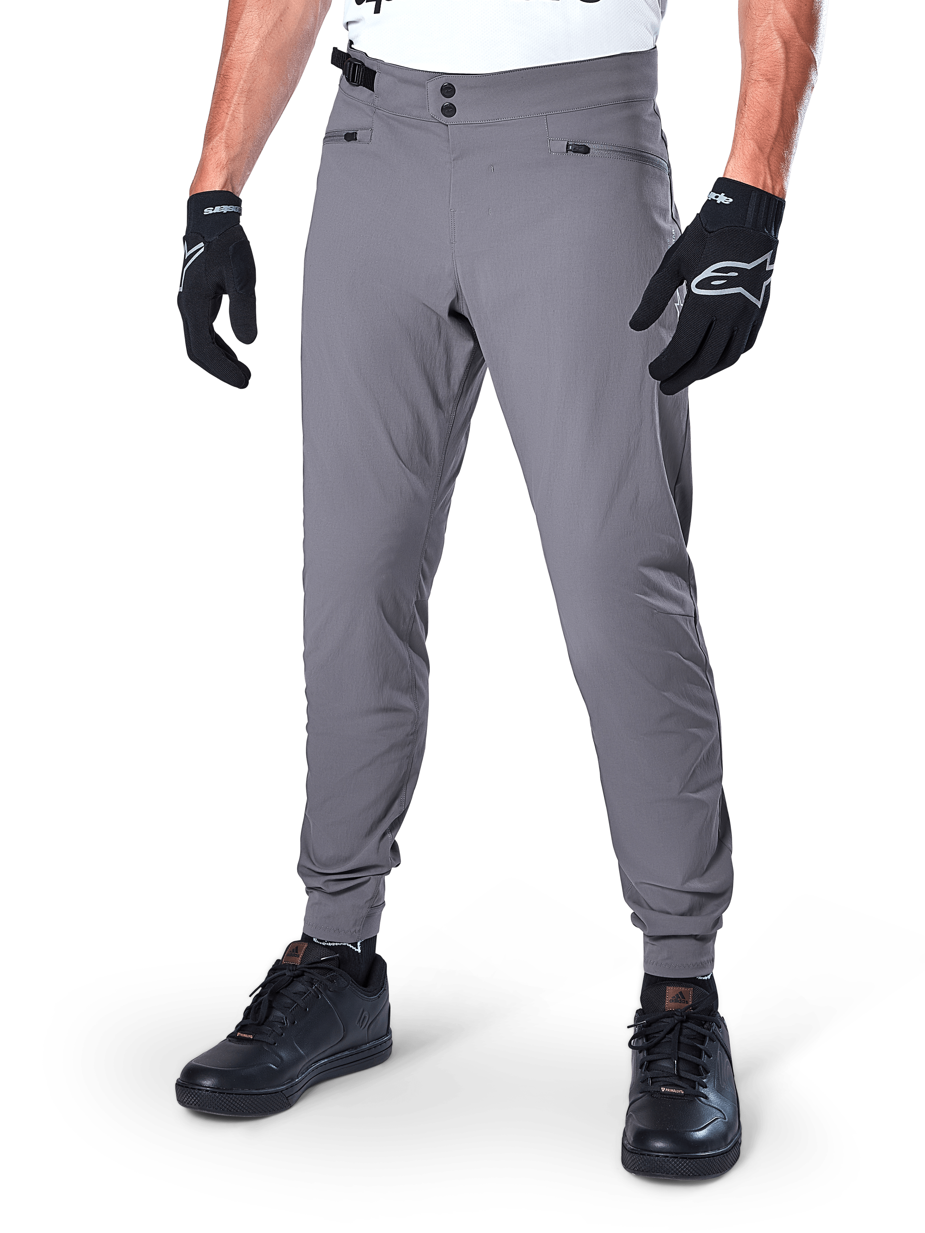 Alpinestars A-Dura Pants, pantalones de MTB gris oscuro, con cierre de cintura de doble broche y bolsillos con cremallera, puños elásticos, usados con guantes de ciclismo negros y zapatillas negras