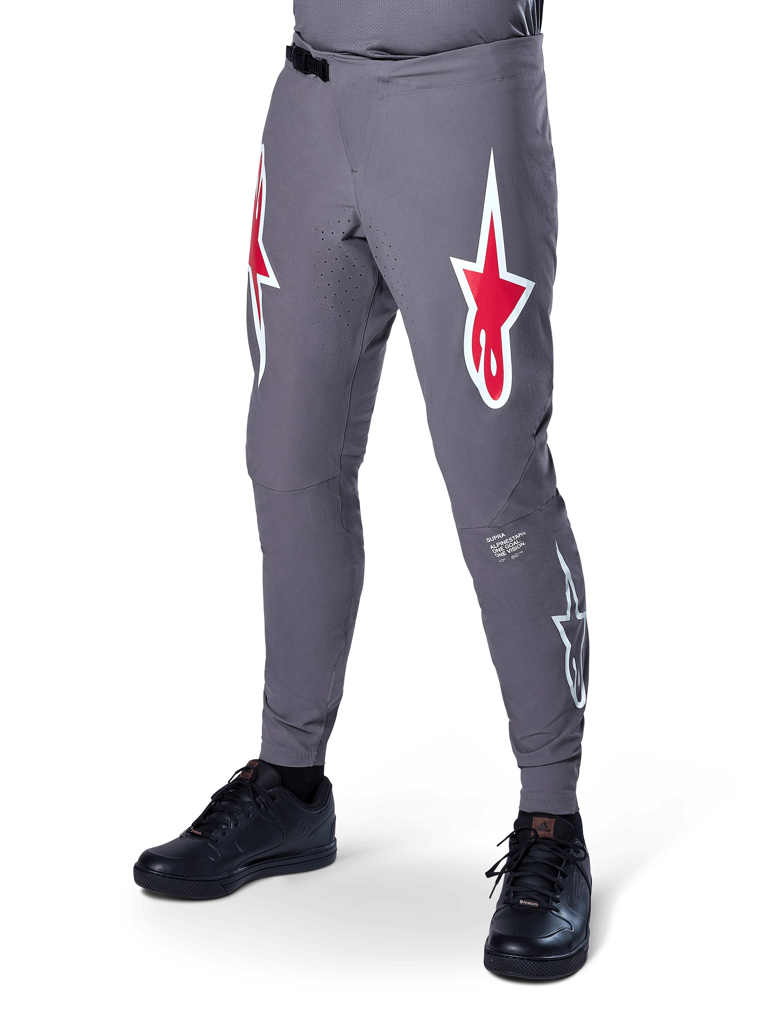Pantalones Alpinestars A-Supra Race, pantalones de ciclismo de montaña en gris oscuro, con grandes logotipos de estrellas en rojo y blanco en los muslos, ventilación perforada con láser y cierre de cintura con trinquete, ajuste de alto rendimiento para descenso y enduro.