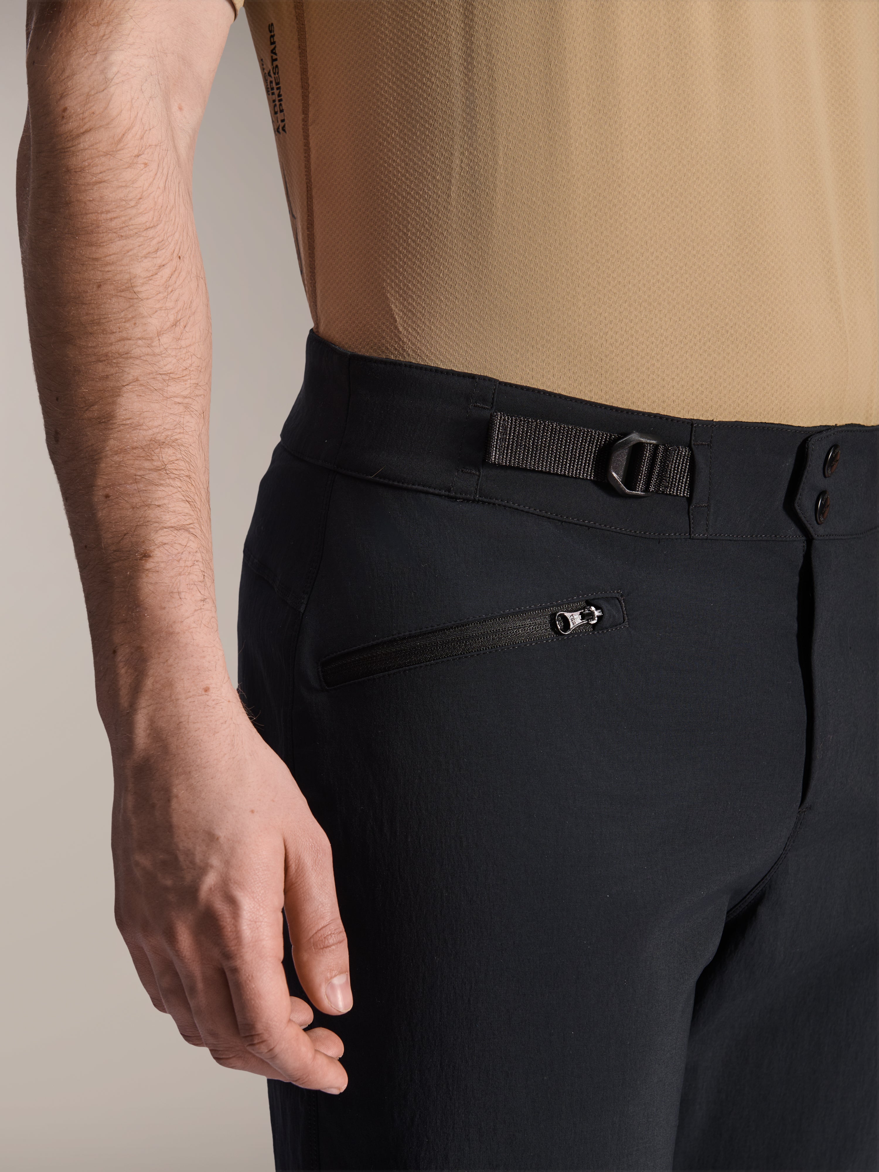 Shorts Alpinestars A-Dura, shorts de MTB negros, vista de cerca que muestra el bolsillo con cremallera y la correa de ajuste lateral, cierre de doble broche, tejido resistente para ciclismo de montaña