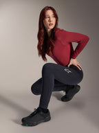 Alpinestars Stella A-Dura Thermal Pants, pantalones de MTB para mujer, negros, usados por una modelo en una pose agachada con una camiseta de manga larga granate y zapatillas de ciclismo negras, con el logotipo de la estrella blanca en el muslo, construcción duradera y cálida para ciclismo todoterreno en climas fríos