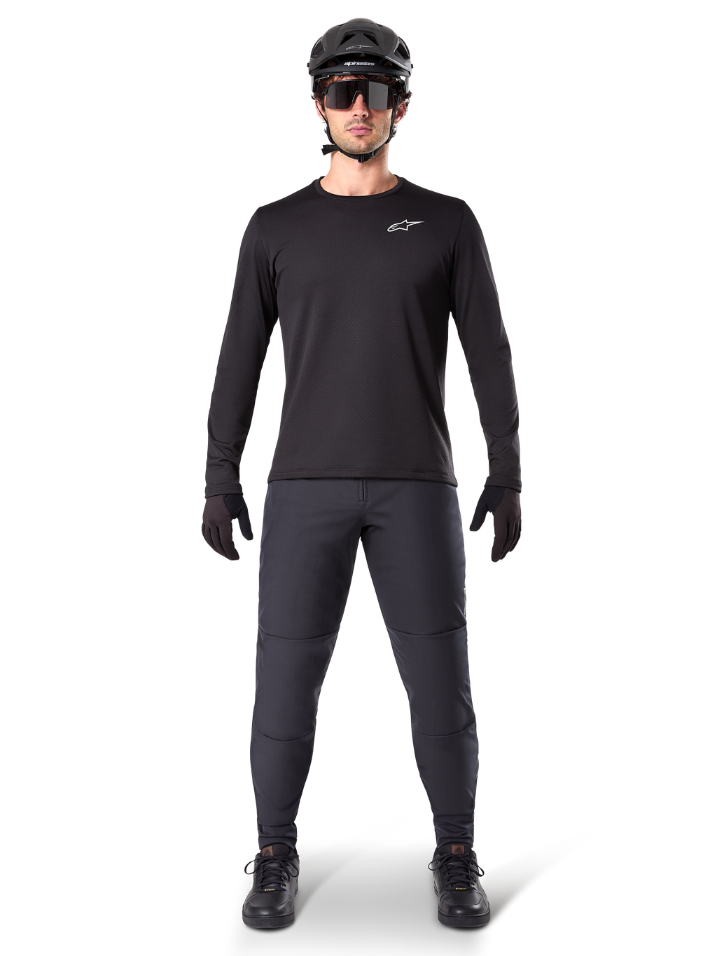 Alpinestars A-Dura Thermal Jersey, jersey de ciclismo de montaña de manga larga, negro, combinado con pantalones gris oscuro, guantes negros, casco negro y gafas de sol, con el logotipo blanco de Alpinestars en el pecho, conjunto coordinado para ciclismo de montaña en climas fríos