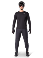 Alpinestars A-Dura Thermal Jersey, jersey de ciclismo de montaña de manga larga, negro, combinado con pantalones gris oscuro, guantes negros, casco negro y gafas de sol, con el logotipo blanco de Alpinestars en el pecho, conjunto coordinado para ciclismo de montaña en climas fríos