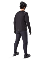 Alpinestars A-Dura Thermal Jersey, jersey de ciclismo de manga larga para hombre, negro, vista trasera del modelo usando casco de MTB negro, pantalones gris oscuro y guantes negros, equipamiento profesional de ciclismo de montaña para clima frío