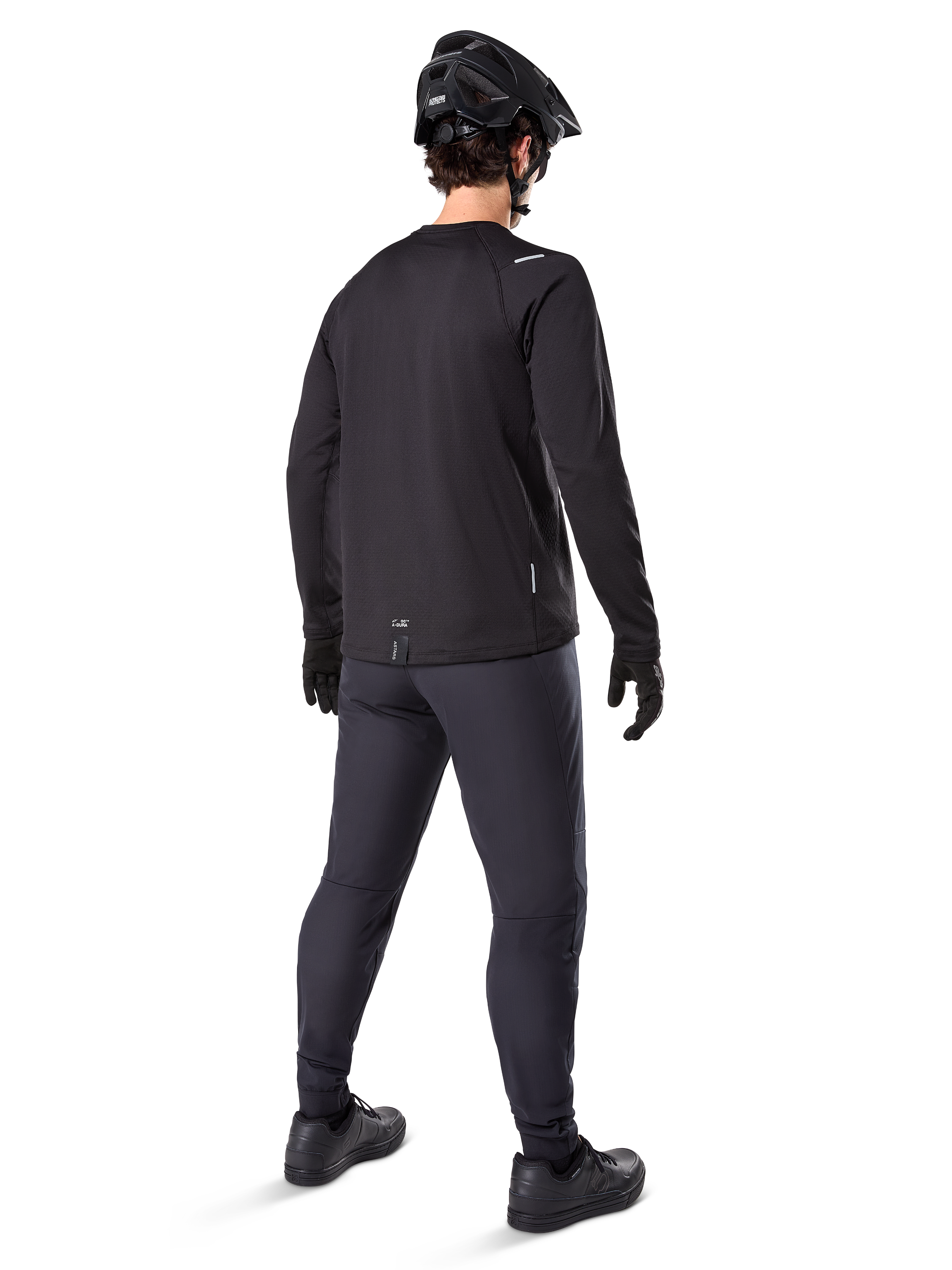 Alpinestars A-Dura Thermal Jersey, jersey de ciclismo de manga larga para hombre, negro, vista trasera del modelo usando casco de MTB negro, pantalones gris oscuro y guantes negros, equipamiento profesional de ciclismo de montaña para clima frío