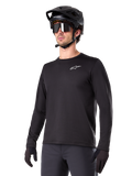 Alpinestars A-Dura Thermal Jersey, jersey de ciclismo de montaña de manga larga, negro con logotipo blanco en el pecho, usado con casco y guantes negros, diseño deportivo y elegante para trail
