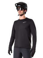 Alpinestars A-Dura Thermal Jersey, jersey de ciclismo de montaña de manga larga, negro con logotipo blanco en el pecho, usado con casco y guantes negros, diseño deportivo y elegante para trail