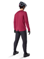 Alpinestars A-Dura Thermal Jersey, jersey de ciclismo de manga larga en color burdeos, vista trasera, combinado con pantalones negros de bicicleta de montaña y casco gris, con dobladillo trasero extendido para mayor cobertura, equipamiento de MTB para clima frío
