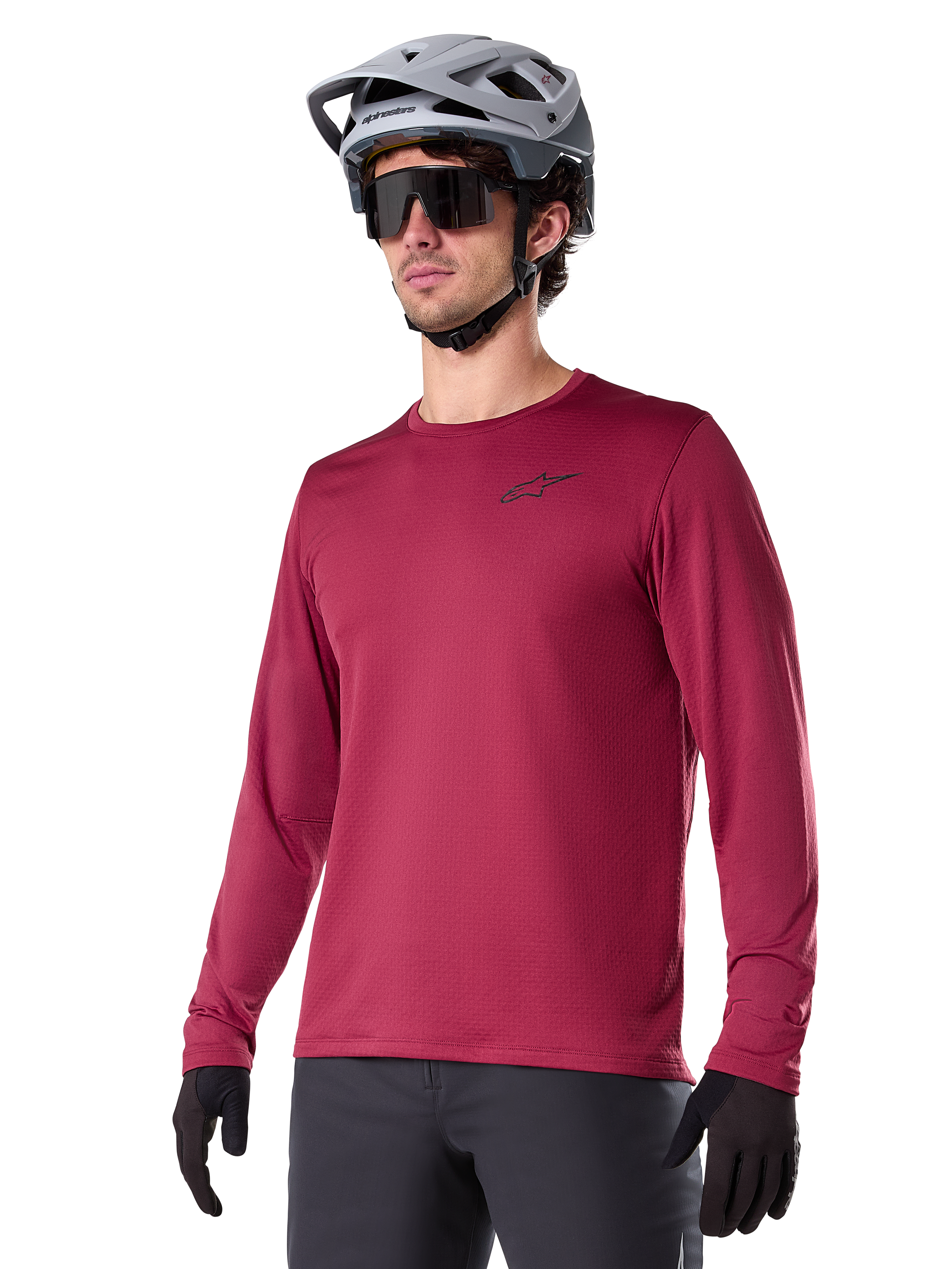 Alpinestars A-Dura Thermal Jersey, jersey de manga larga para ciclismo de montaña, rojo borgoña, con forro polar aislante y un pequeño logotipo negro en el pecho, usado con un casco gris, gafas de sol negras y guantes negros, diseñado para ciclismo en climas fríos