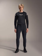 Modelo masculino con la camiseta de manga larga Alpinestars A-Aria Polartec Elite en color negro, con logotipo Astars blanco en el pecho y marca en los hombros, combinada con pantalones técnicos de MTB y calzado negro, equipamiento de alto rendimiento para bicicleta de montaña