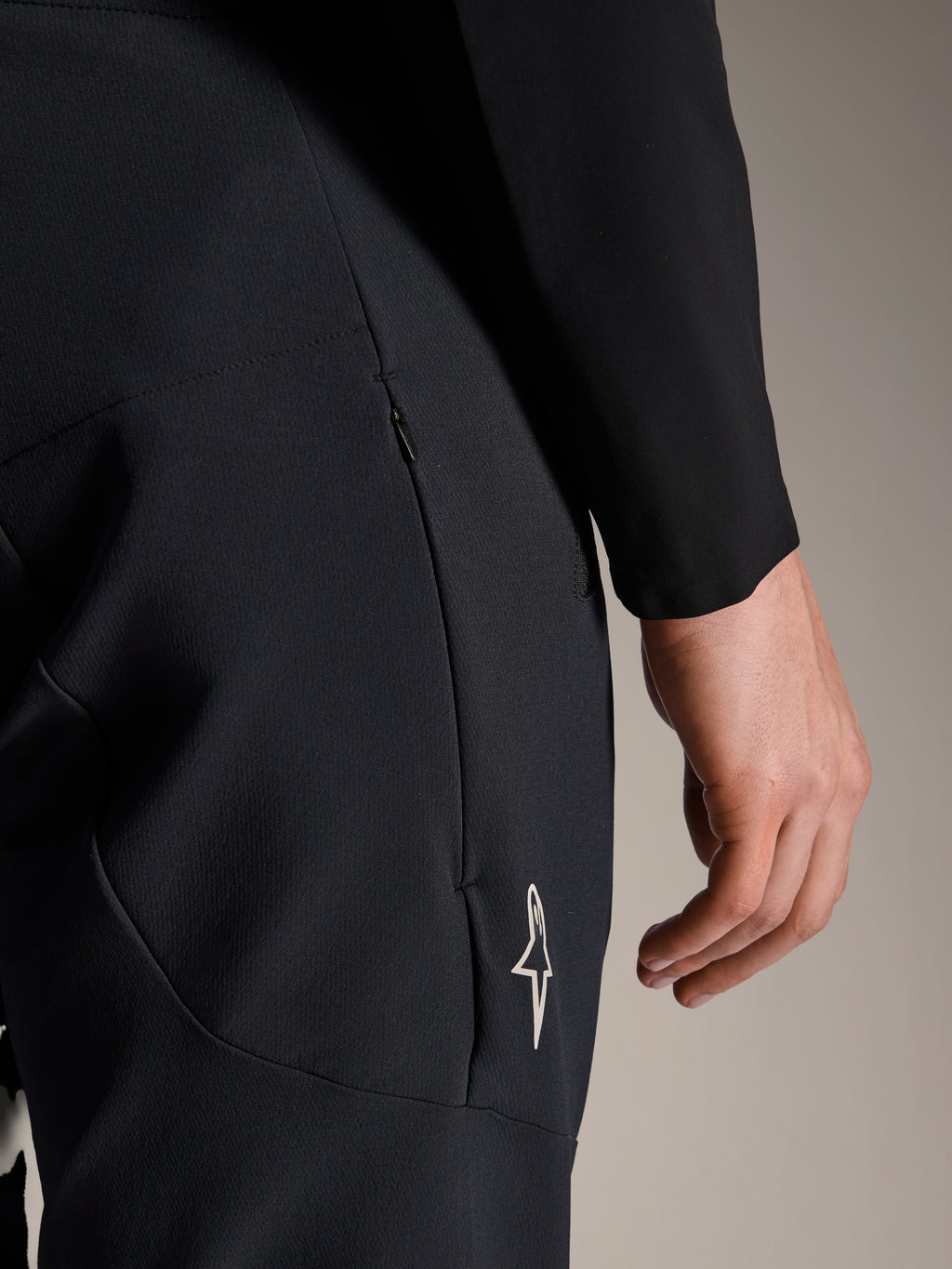 Primer plano de los pantalones Alpinestars A-Aria Elite en Black Titanium, con un bolsillo lateral con cremallera y un pequeño logo de estrella blanca, pantalones técnicos de montaña diseñados para ciclismo de alto rendimiento