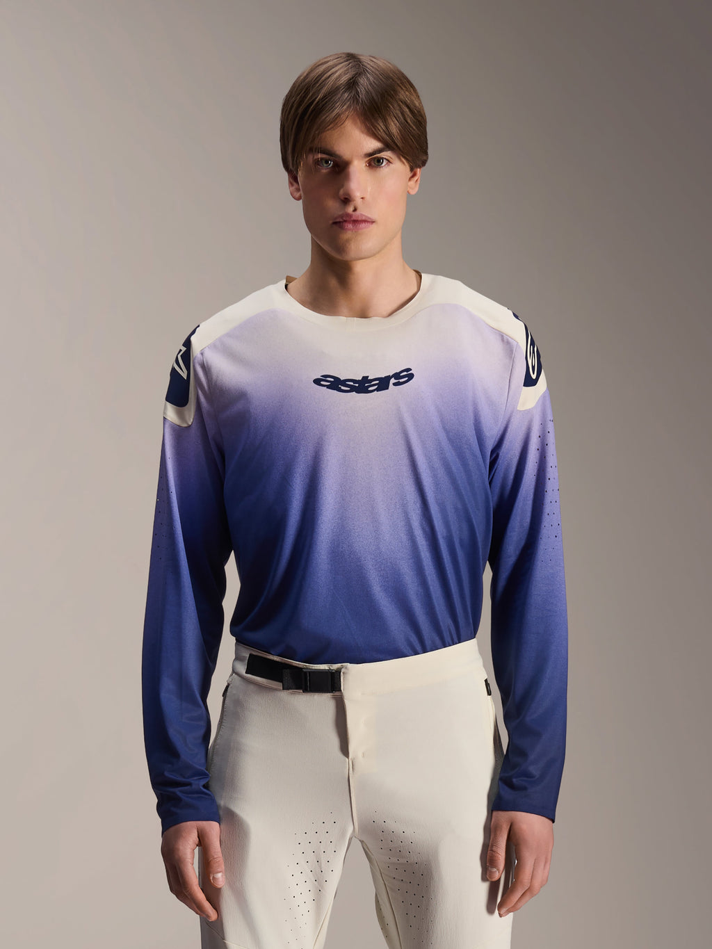 Alpinestars A-Aria Polartec Maker Elite Jersey, jersey de MTB de manga larga, color Baja Blue con degradado de blanco a azul, usado por un modelo con pantalones blancos, con logotipo azul oscuro en el pecho y perforaciones láser en las mangas, ropa de ciclismo de montaña de alto rendimiento