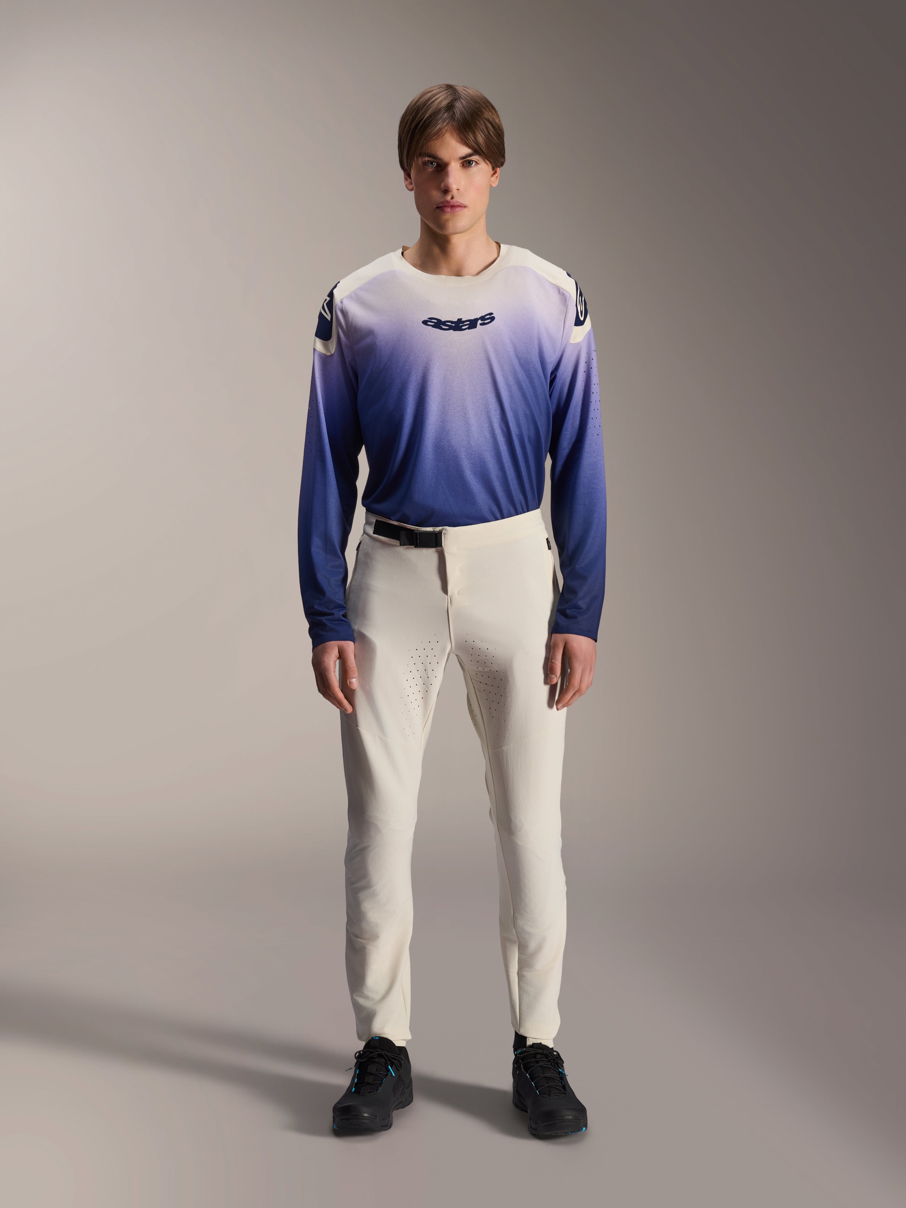 Alpinestars A-Aria Elite Pants, Ecru Performance MTB Pants, off-white cycling trousers with laser-perforated thigh panels and magnetic buckle, worn with gradient blue long-sleeve jersey and black shoes, performance fit for trail riding
