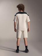 Jersey de manga corta Alpinestars A-Aria Polartec Elite, jersey de ciclismo MTB, color crudo con paneles negros en los hombros, vista trasera mostrada con pantalones cortos a juego y calcetines negros, ajuste de rendimiento con un diseño de cola caída para conducción fuera de carretera.