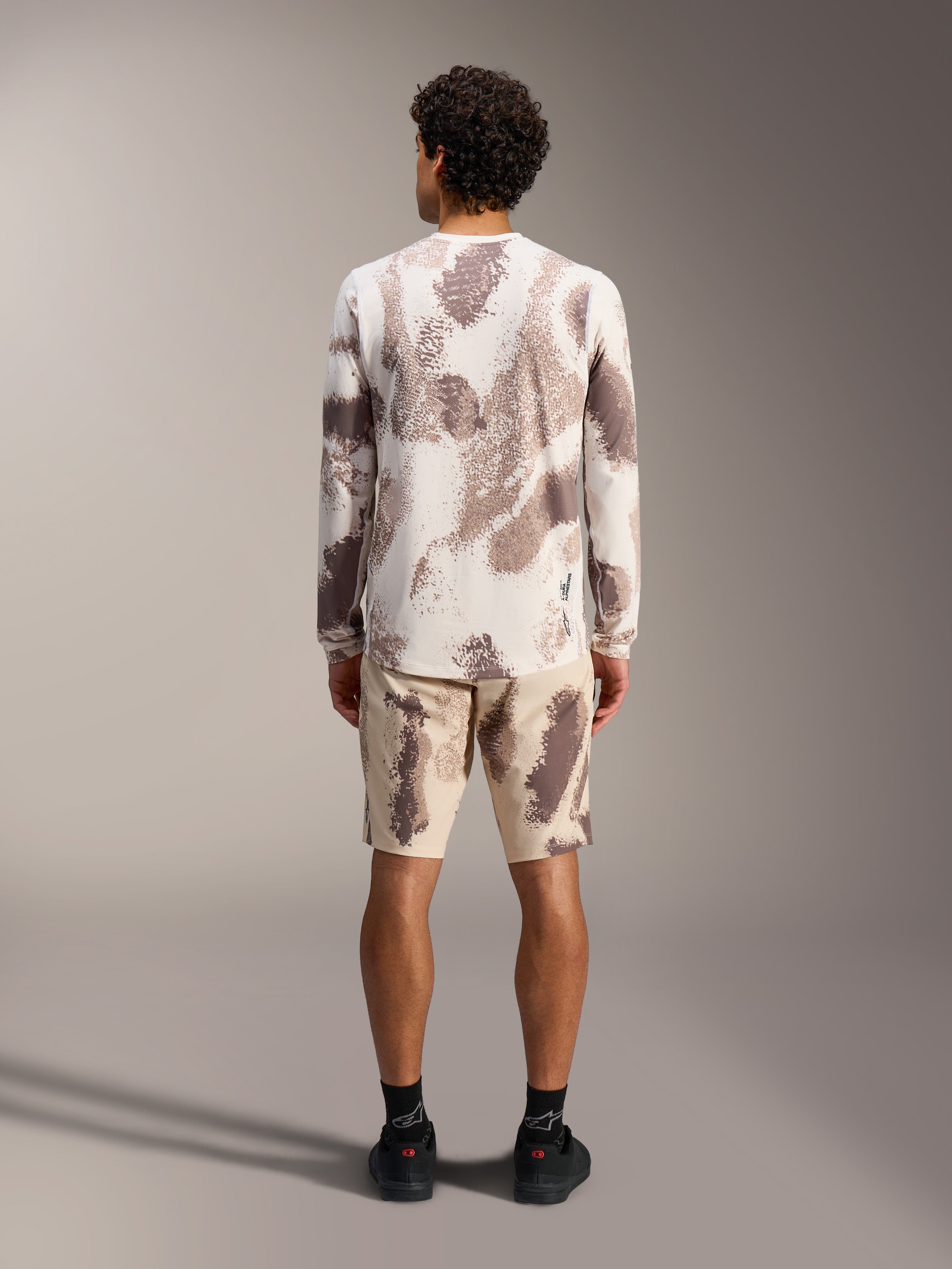 Alpinestars A-Dura Ride LS Jersey and matching shorts in sand camo pattern, styled as a complete MTB outfit, rear view.