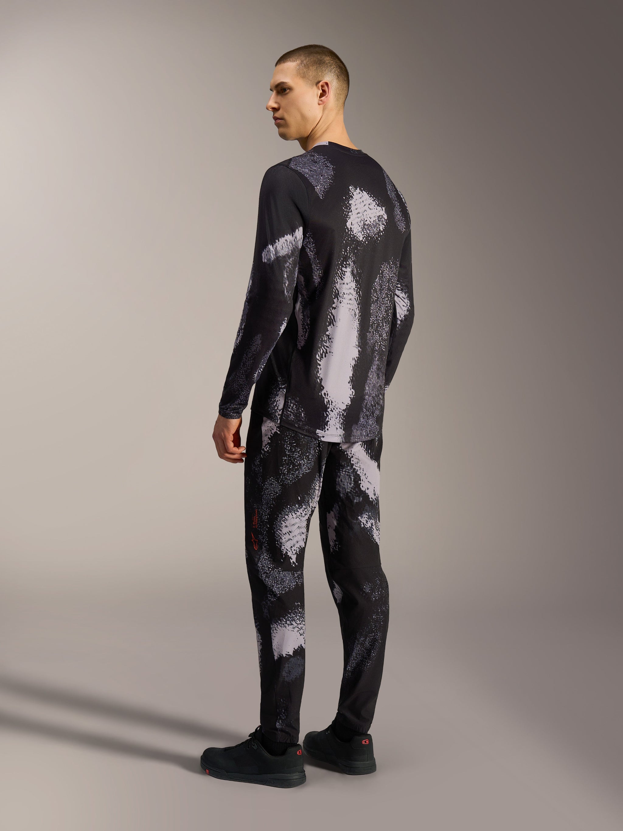 Jersey Alpinestars A-Dura Ride de manga larga en Black Camo, prenda técnica de MTB con patrón abstracto sobre modelo.