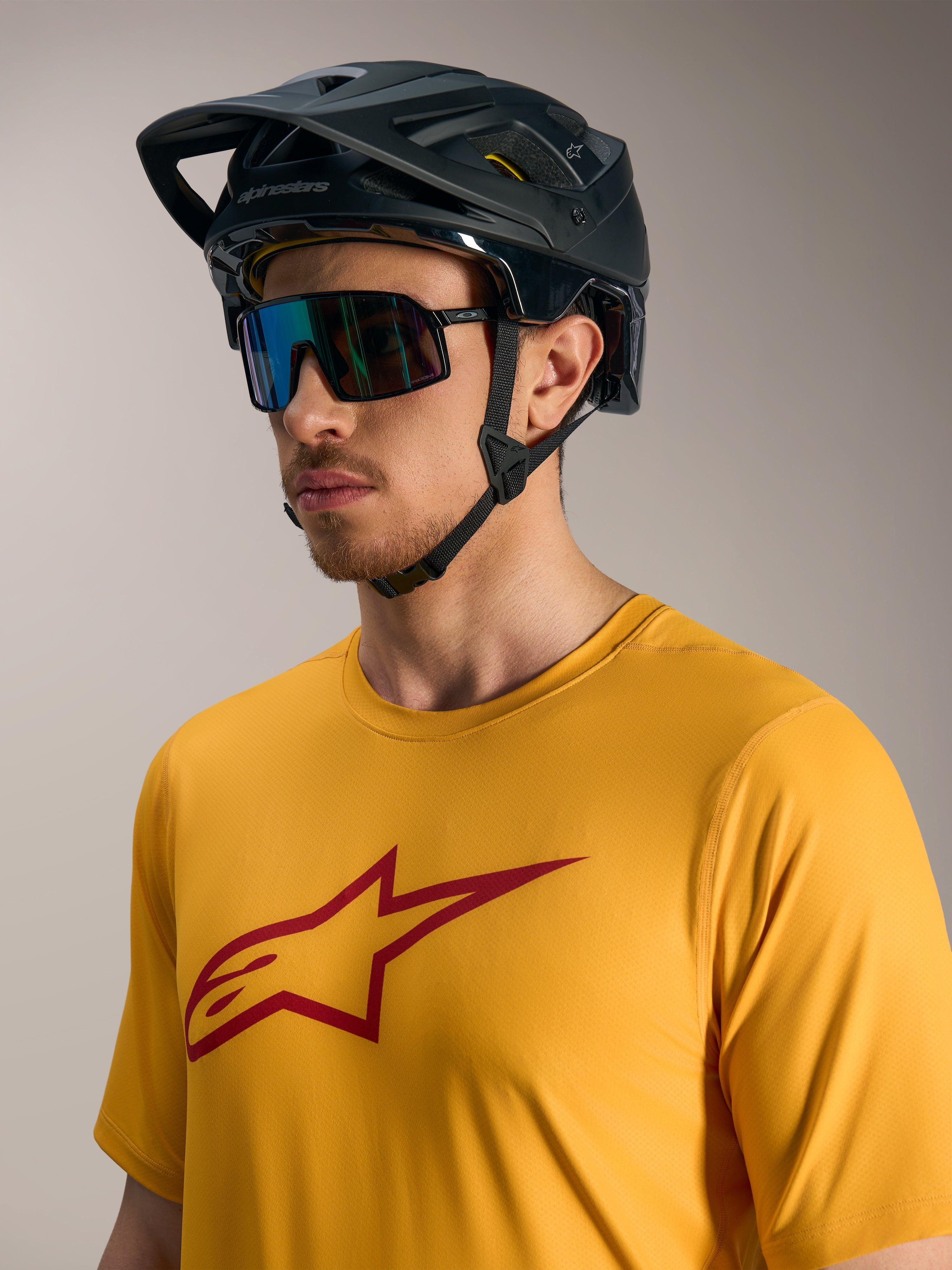 Camiseta Alpinestars A-Dura Ride naranja con logo Astars rojo, casco de MTB negro y gafas de sol de alto rendimiento