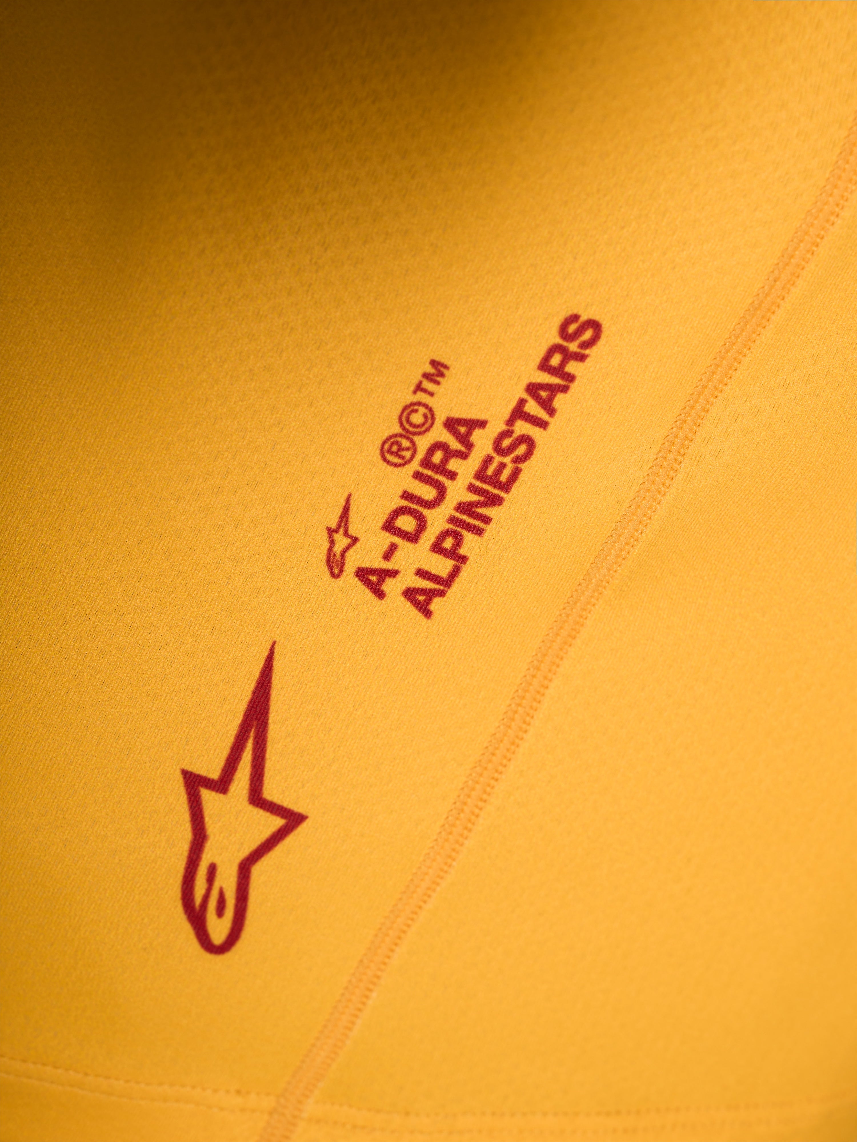 Jersey A-Dura Ride naranja, con detalle del logotipo Astars y marca Alpinestars en rojo serigrafiados sobre tejido elástico.