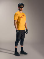 Camiseta Alpinestars A-Dura Ride naranja con logo rojo, equipo de montaña negro y casco de ciclismo.