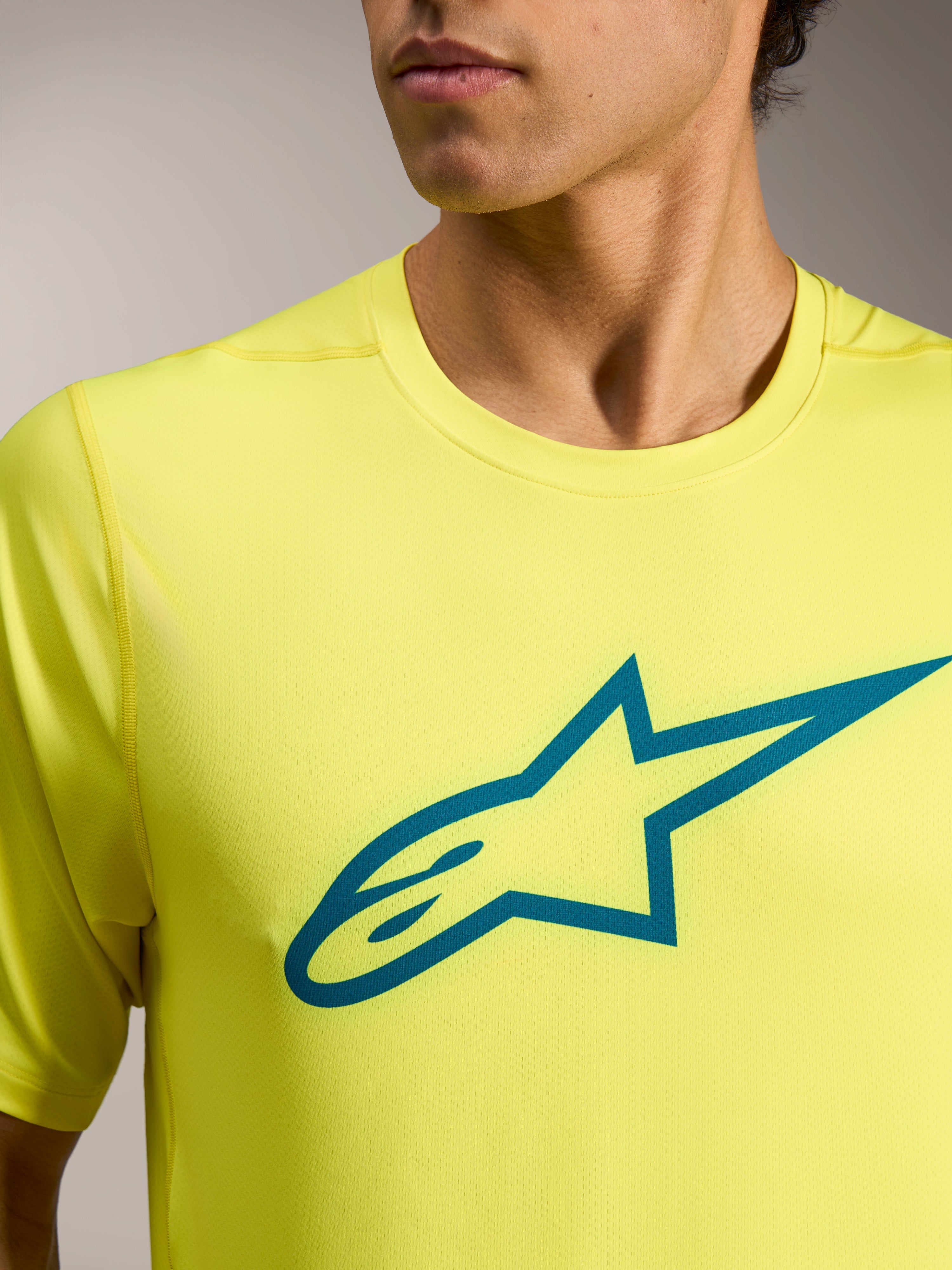 Camiseta A-Dura Ride amarilla flúor con logotipo Astars verde azulado en el pecho, equipación técnica ligera de MTB