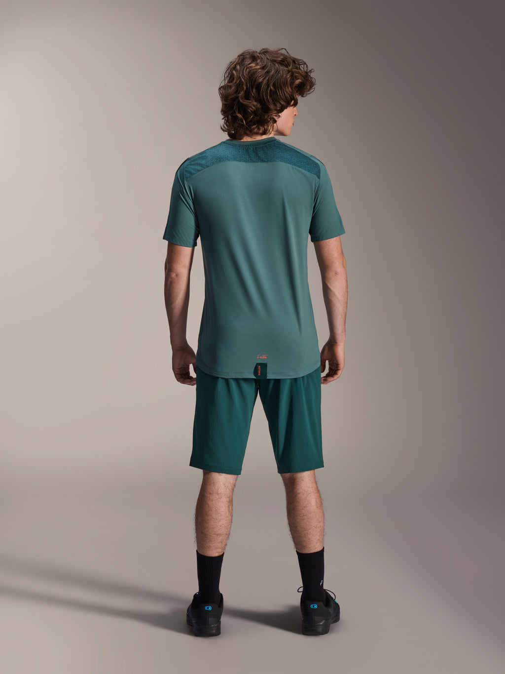 Alpinestars A-Dura Shorts y Jersey A-Dura Lipan SS, color verde Dark Pine, vista trasera en un modelo, ropa de alto rendimiento para bicicleta de montaña que incluye jersey de manga corta y shorts a juego, equipación de ciclismo off-road